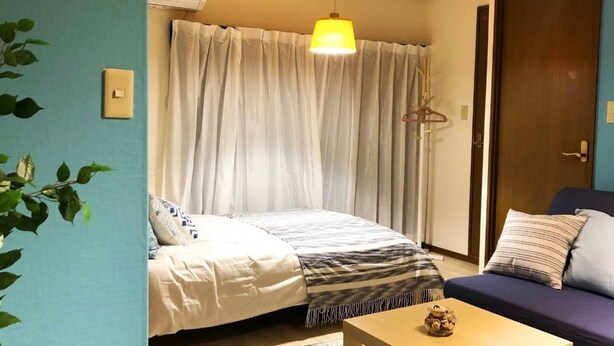 Un dormitorio con cama, sofá, lámpara colgante y una planta.