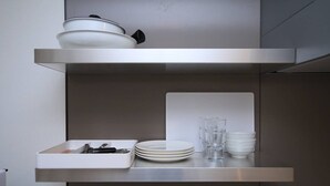 A kitchen with a stainless steel countertop, a white dish rack, and a white cutting board. - Prosper Rainbow Villa (Osaka)