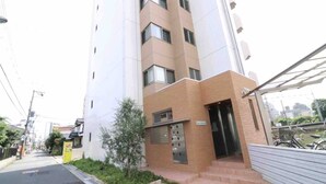 A multi-story building with a modern design, featuring a brick facade and a glass entrance. - Prosper Rainbow Villa (Osaka)