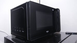 Un horno microondas Haier negro sobre una superficie oscura.