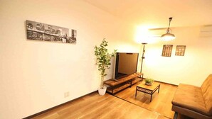 A living room with a sofa, a coffee table, a TV, and a plant. - Sky Terrace Kujyo (Osaka)