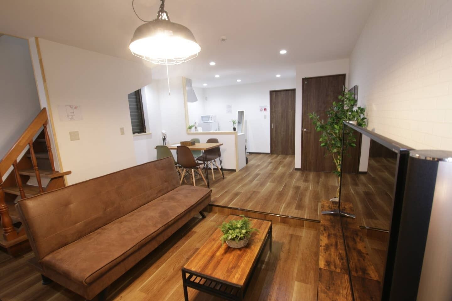 A modern living room with a brown sofa, wooden coffee table, and a hanging light fixture.