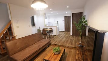 A modern living room with a brown sofa, wooden coffee table, and a hanging light fixture.