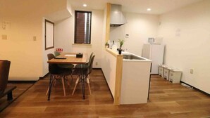 A compact kitchen with a dining area, a microwave, a refrigerator, and a small sink. - Sky Terrace Kujyo (Osaka)