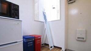 Eine Küche mit Mikrowelle, zwei Mülleimer, einem Fenster und einem an der Wand befestigten Luftreiniger.