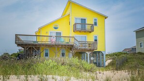 A yellow two-story building with a balcony and a sign indicating it is a restaurant. - Sun Trippin' | Oceanfront Escape in South Nags Head with Private Beach Access & Panoramic Views (South Nags Head)