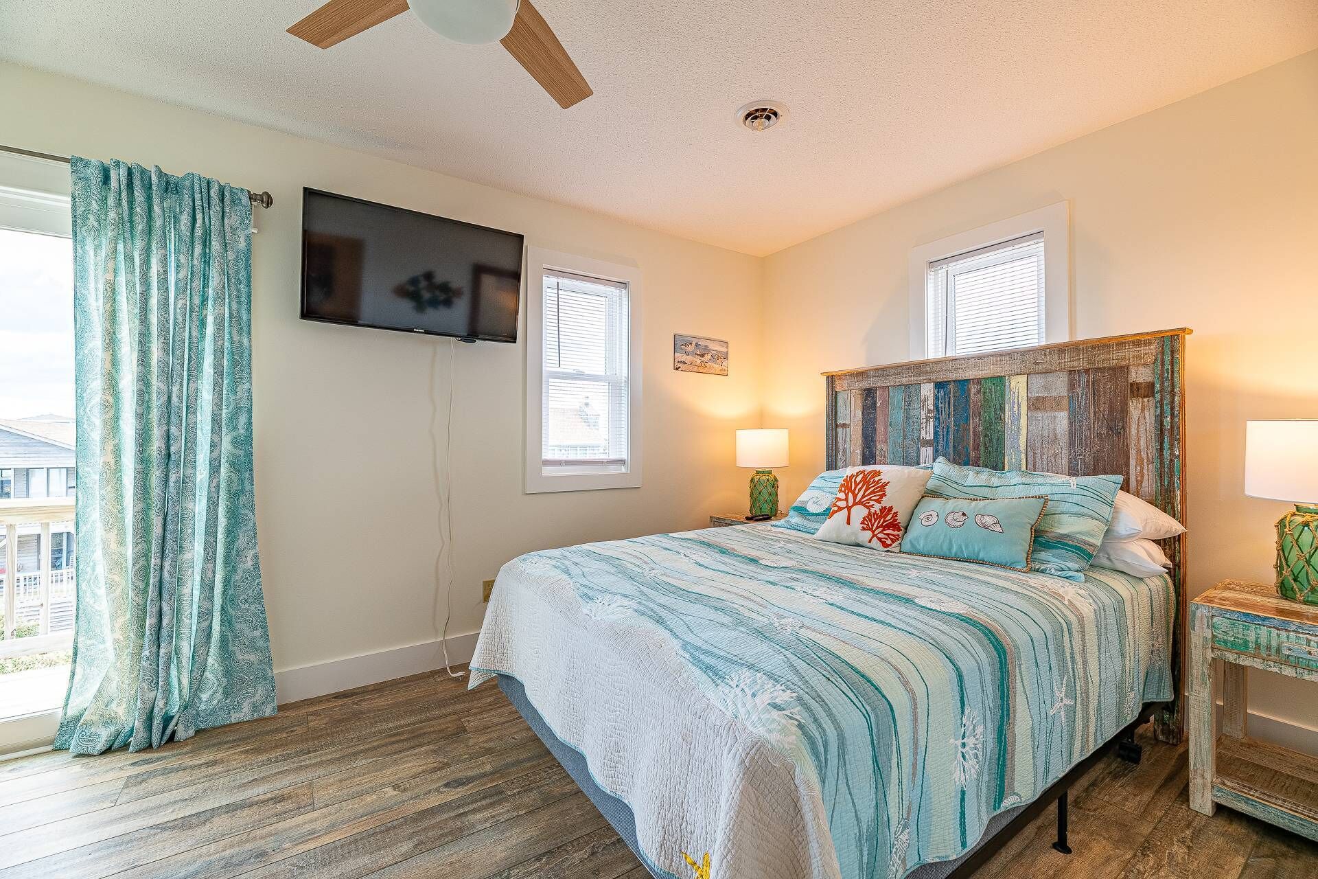 A bedroom with a bed, a TV, and a ceiling fan.