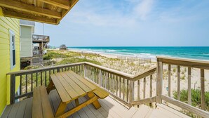 A wooden deck with a picnic table overlooking a beach with a clear view of the ocean. - Sun Trippin' | Oceanfront Escape in South Nags Head with Private Beach Access & Panoramic Views (South Nags Head)