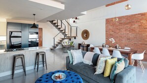 A modern living space with a kitchen, dining area, and staircase. - The Bond Square (Durban)