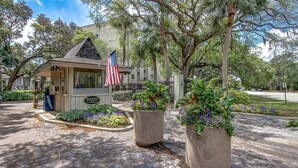 A small building with an American flag, surrounded by trees and potted plants.