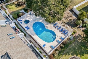 Vue aérienne d’une propriété résidentielle dotée d’une piscine, de chaises longues et d’un jardin clos.