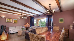 A spacious living room with a wooden dining table, wicker chairs, and a sofa set. - Spacious  holiday house - pool / jacuzzi / sauna / playground / 8+2 (Rakalj)