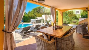 A covered outdoor area with a pool, lounge chairs, a table with bottles and glasses, and wicker furniture. - Spacious  holiday house - pool / jacuzzi / sauna / playground / 8+2 (Rakalj)