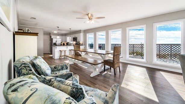 A spacious living area with a dining table, comfortable seating, and large windows offering a view of the outdoors.