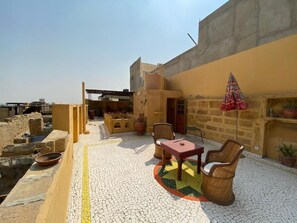 A rooftop patio with a mosaic floor, outdoor seating, and a view of the cityscape.