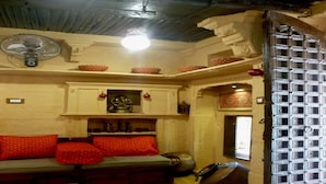 Una habitación tradicional con sofá, ventilador y una puerta decorativa.