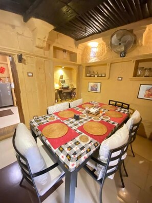 A dining area with a table set for four, surrounded by chairs with cushions.