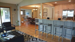 A spacious kitchen with a bar area, wooden cabinets, and a stainless steel refrigerator. - Lakeside Leisure: Relax, Recharge, Reconnect! (Alexandria)