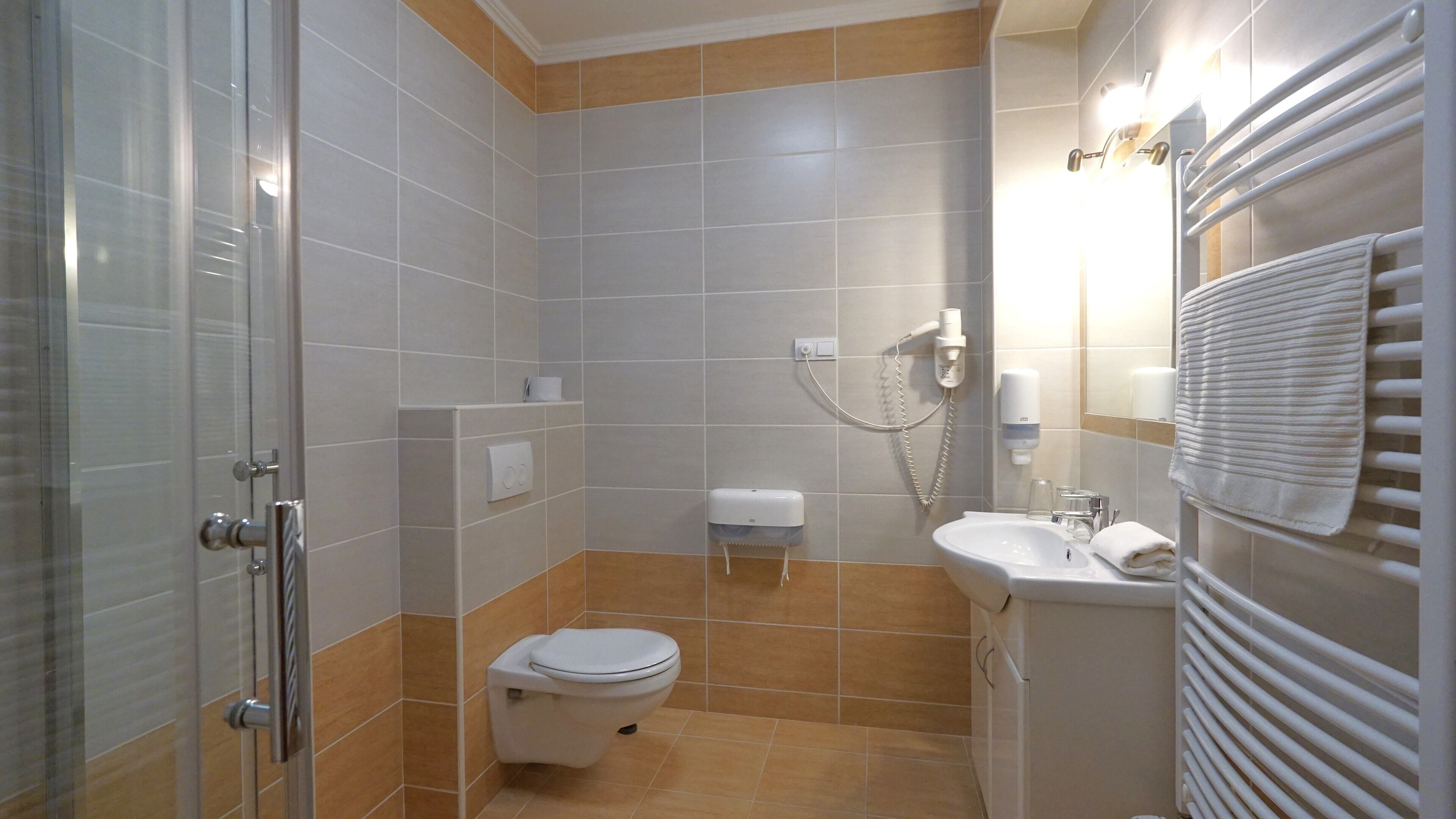 A compact bathroom with a toilet, sink, and shower area.