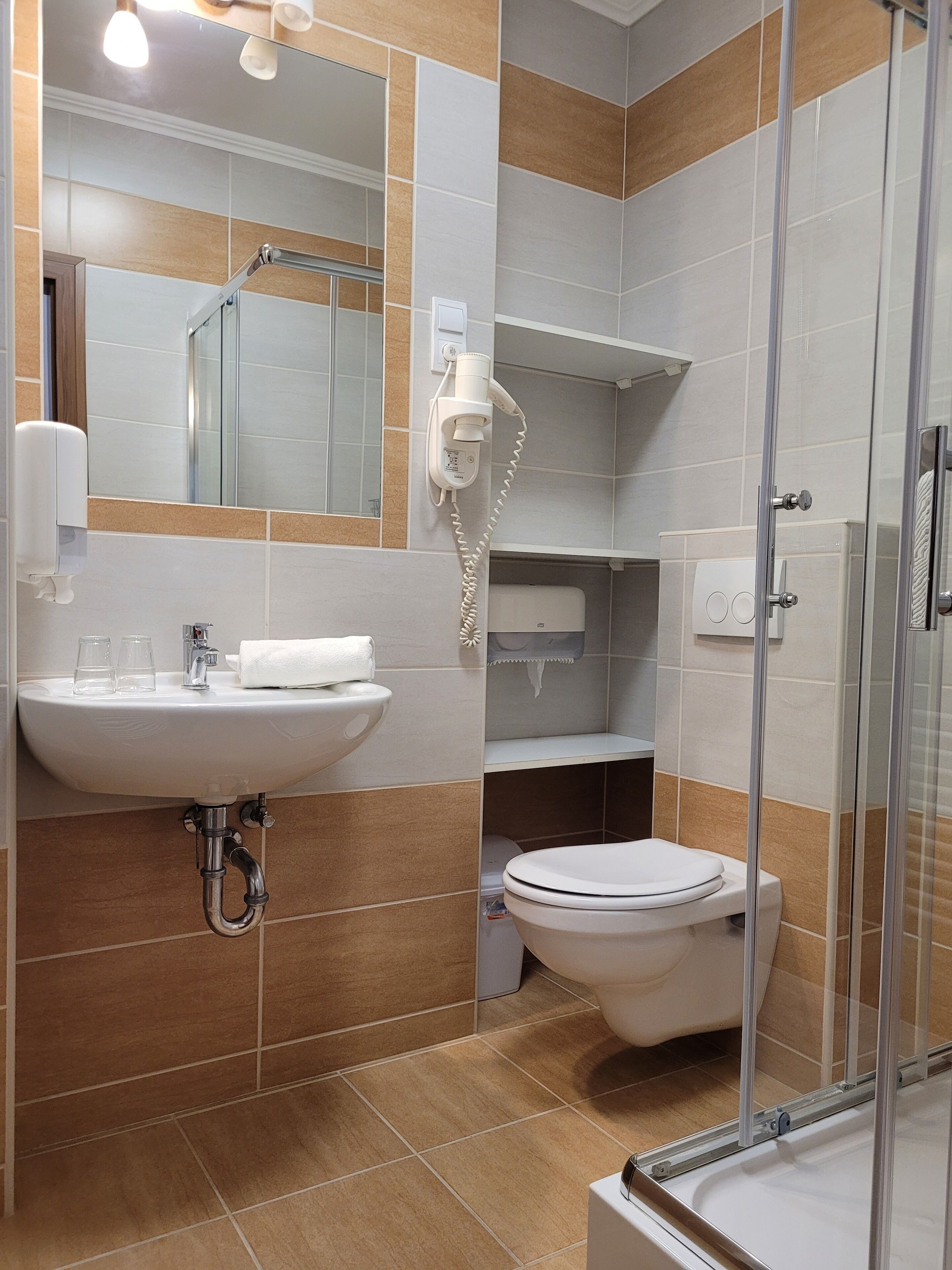 Une salle de bain moderne équipée d’un lavabo, d’un miroir, de toilettes et d’un espace douche.