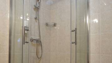 Cabina de ducha con paredes de azulejos naranja y suelo blanco.