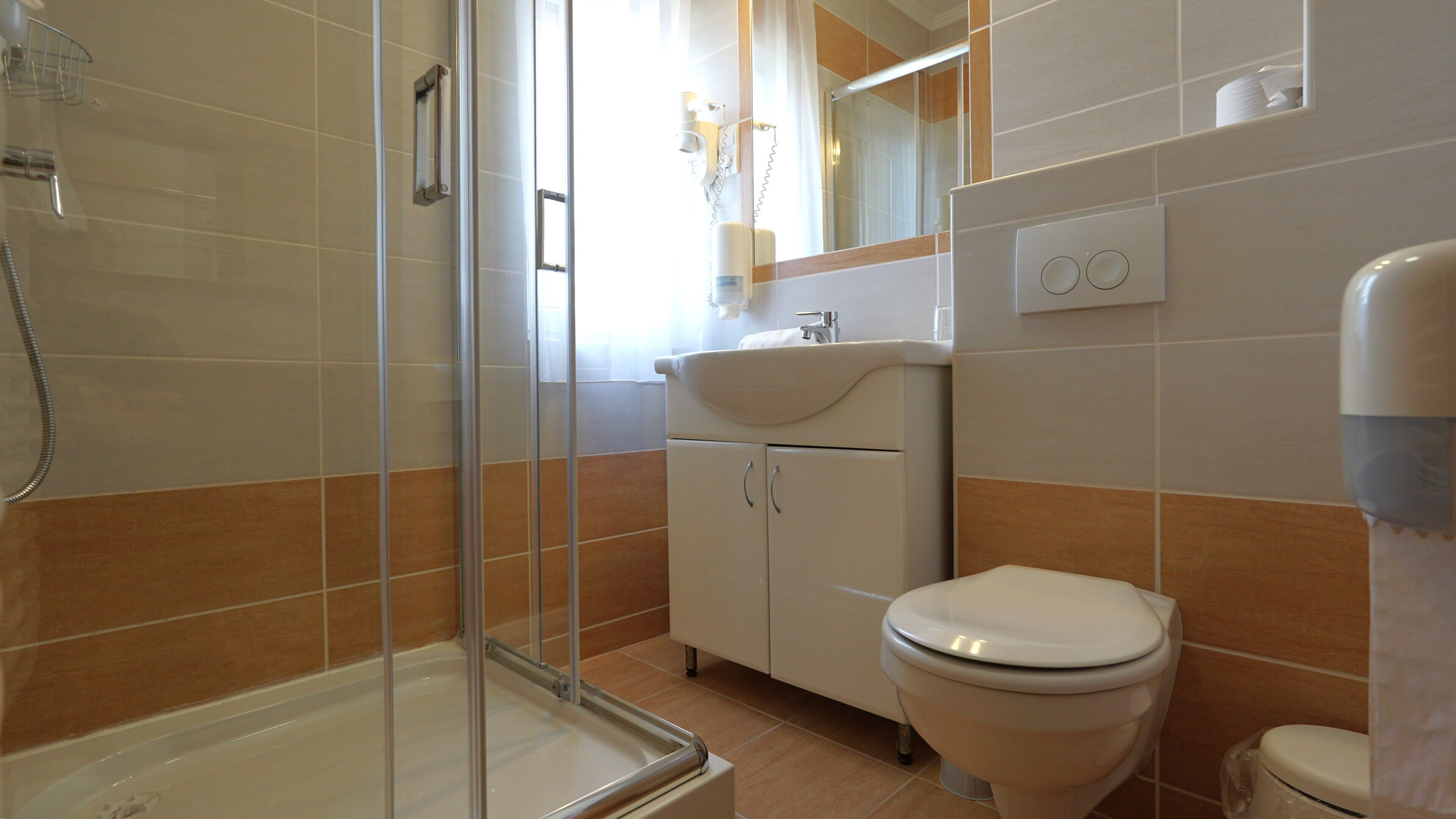 A bathroom with a shower, toilet, sink, and cabinet.
