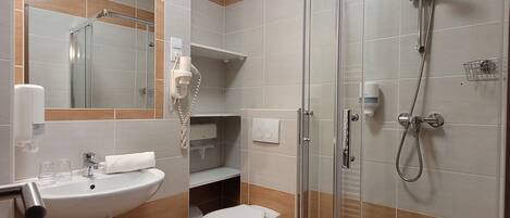 Un baño moderno con ducha de vidrio, lavabo con espejo y retrete.