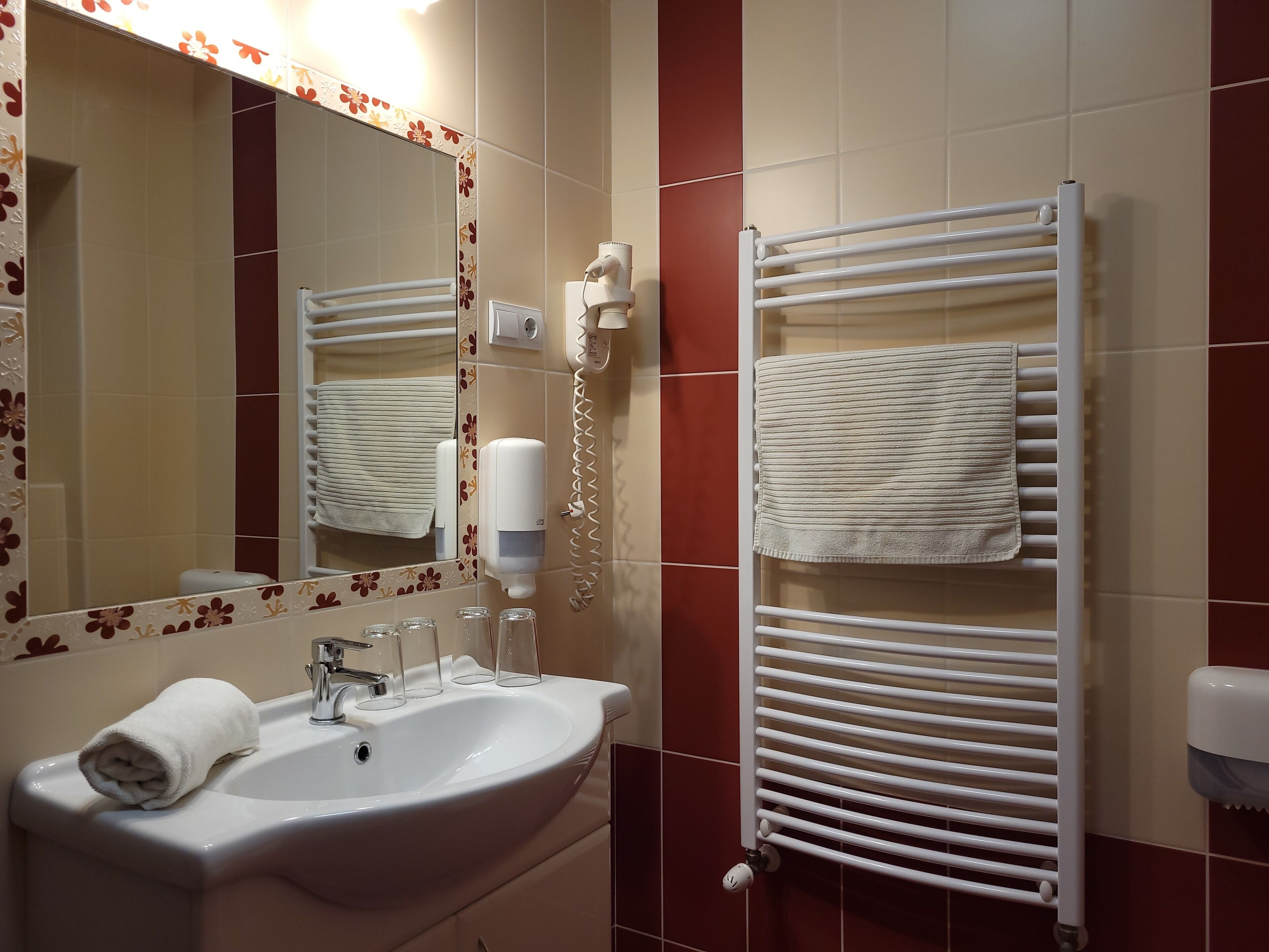 A bathroom with a sink, mirror, towel rack, and hand dryer.