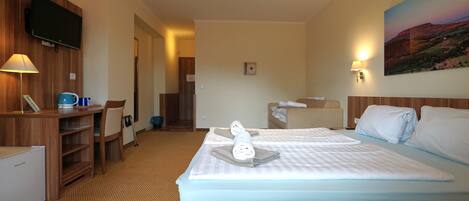 A hotel room with two beds, a desk, a television, and a painting on the wall.