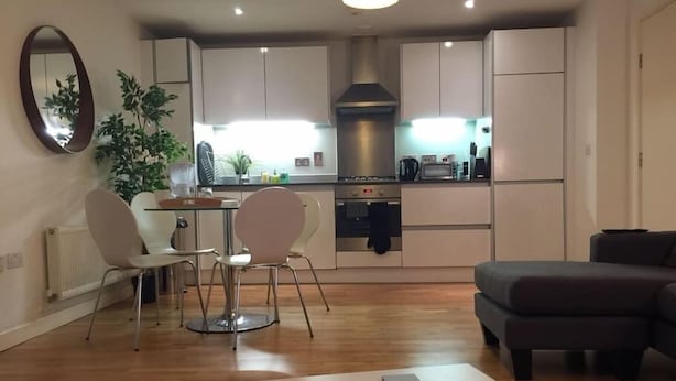 A modern kitchen with white cabinets, a central island, and a dining area with two chairs. - Hunsaker Suite, Reading Serviced Apartment (Reading)