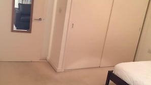 A bedroom with a single bed, a dark rug, a wardrobe, and a mirror on the door. - Hunsaker Suite, Reading Serviced Apartment (Reading)