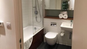 A modern bathroom with a glass-enclosed shower, a white bathtub, a toilet, and a sink with a mirror above. - Hunsaker Suite, Reading Serviced Apartment (Reading)