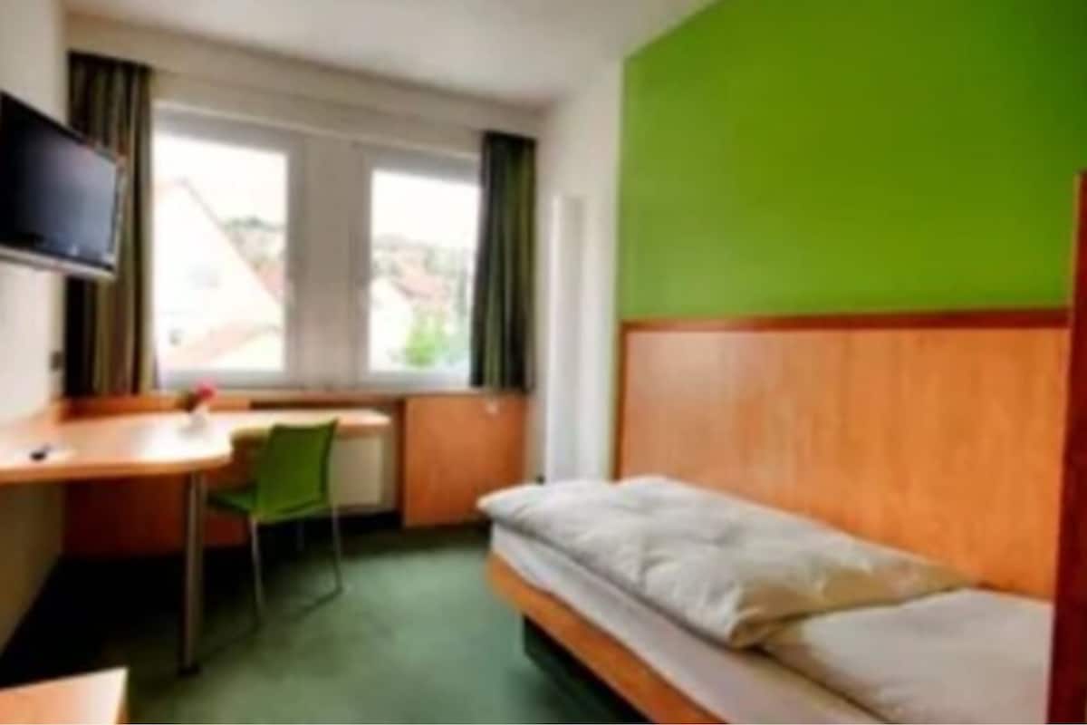 Une chambre d’hôtel avec un lit, un bureau, une chaise et un téléviseur.
