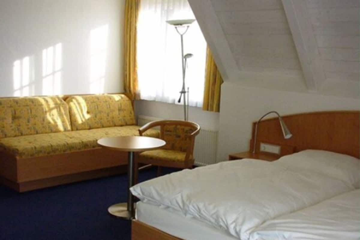 Une chambre d’hôtel avec un lit, un canapé, une chaise et une petite table.