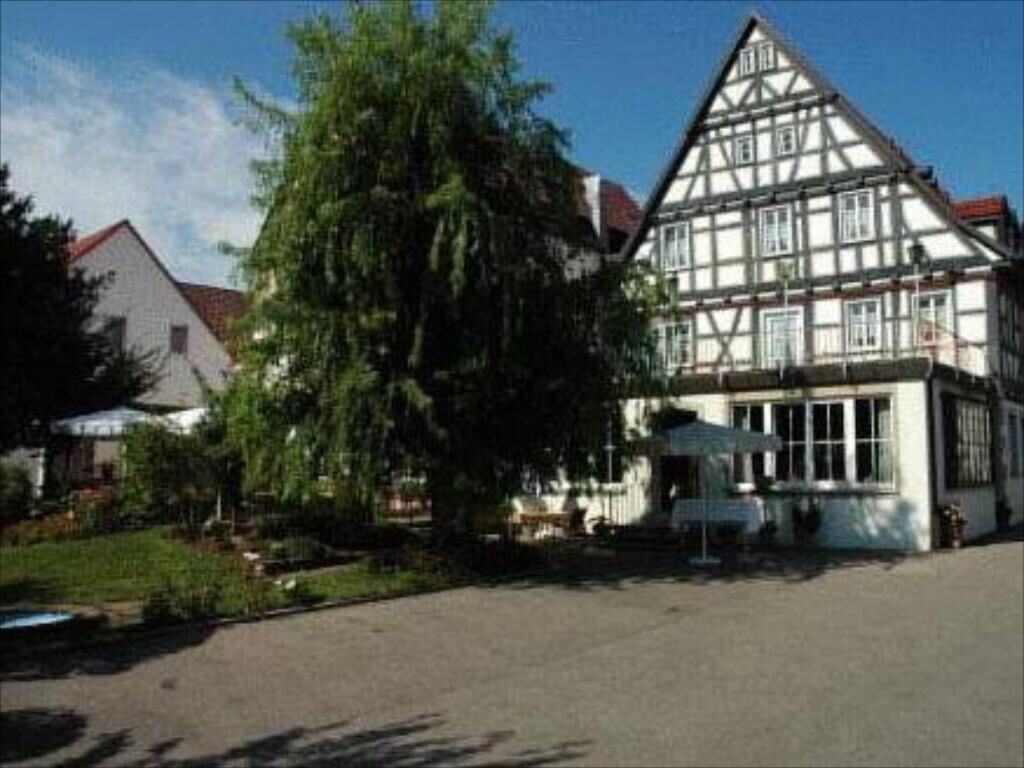 Ein traditionelles Fachwerkhäuschen mit einem großen Baum davor.