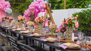 A long dining table set with glassware, plates, and pink floral centerpieces. - Villandro Residence (Accra)