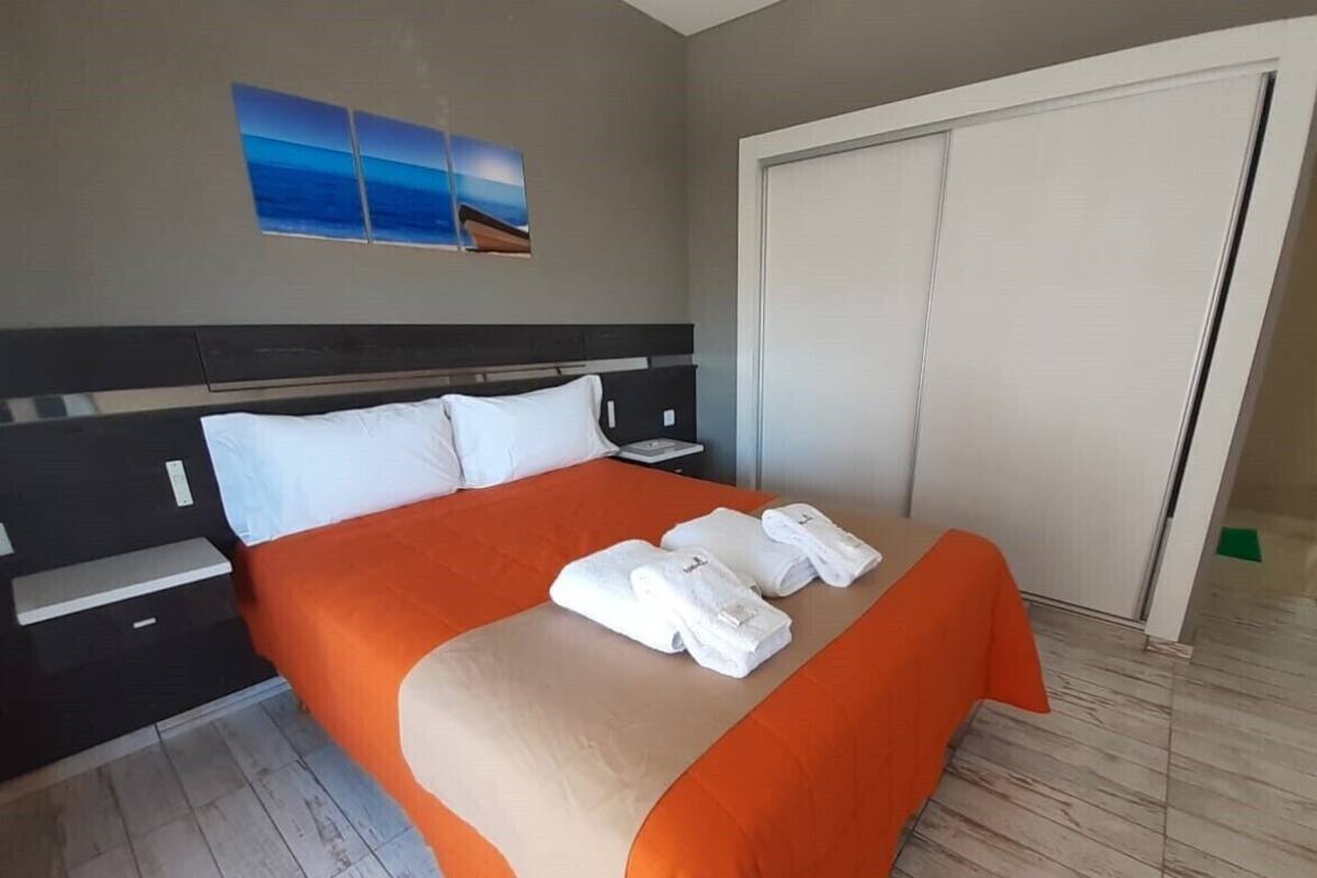 A hotel room with a bed, a nightstand, a wardrobe, and a painting on the wall.