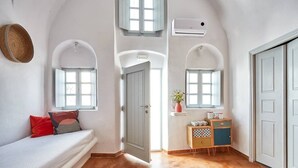 A bedroom with a bed, a small desk, and a window. - Santorini-treasures Rockside Villa traditional (Emporio)