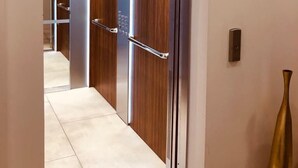 An elevator with a digital display, wooden interior, and a metallic handle.