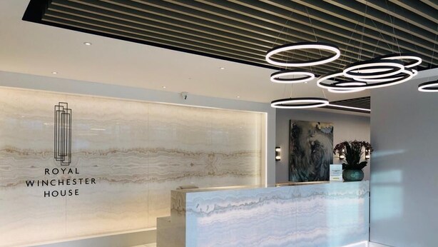 A reception area with a marble wall, a reception desk, and modern circular light fixtures.