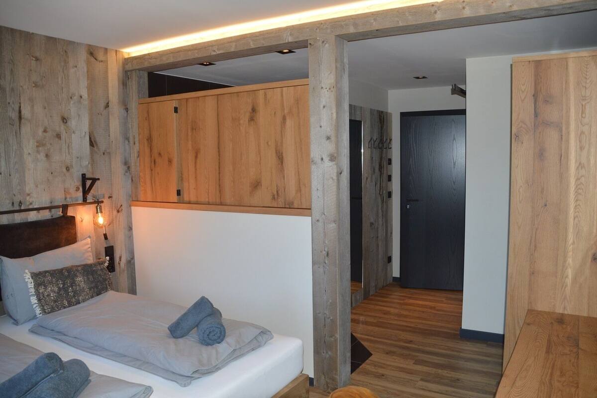 Ein Schlafzimmer mit einem hölzernen Kopfteil, einem Bett mit grauer Bettwäsche und einem Nachttisch mit einer Lampe.