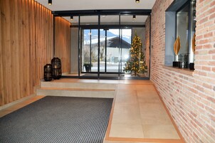 Un moderno vestíbulo con una pared de madera, un vidrio que da al exterior, un árbol de Navidad y una pared de ladrillo con una ventana.
