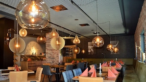 A restaurant interior with round tables, chairs, and hanging spherical light fixtures. - Hotel Herz3 (Hollersbach im Pinzgau)