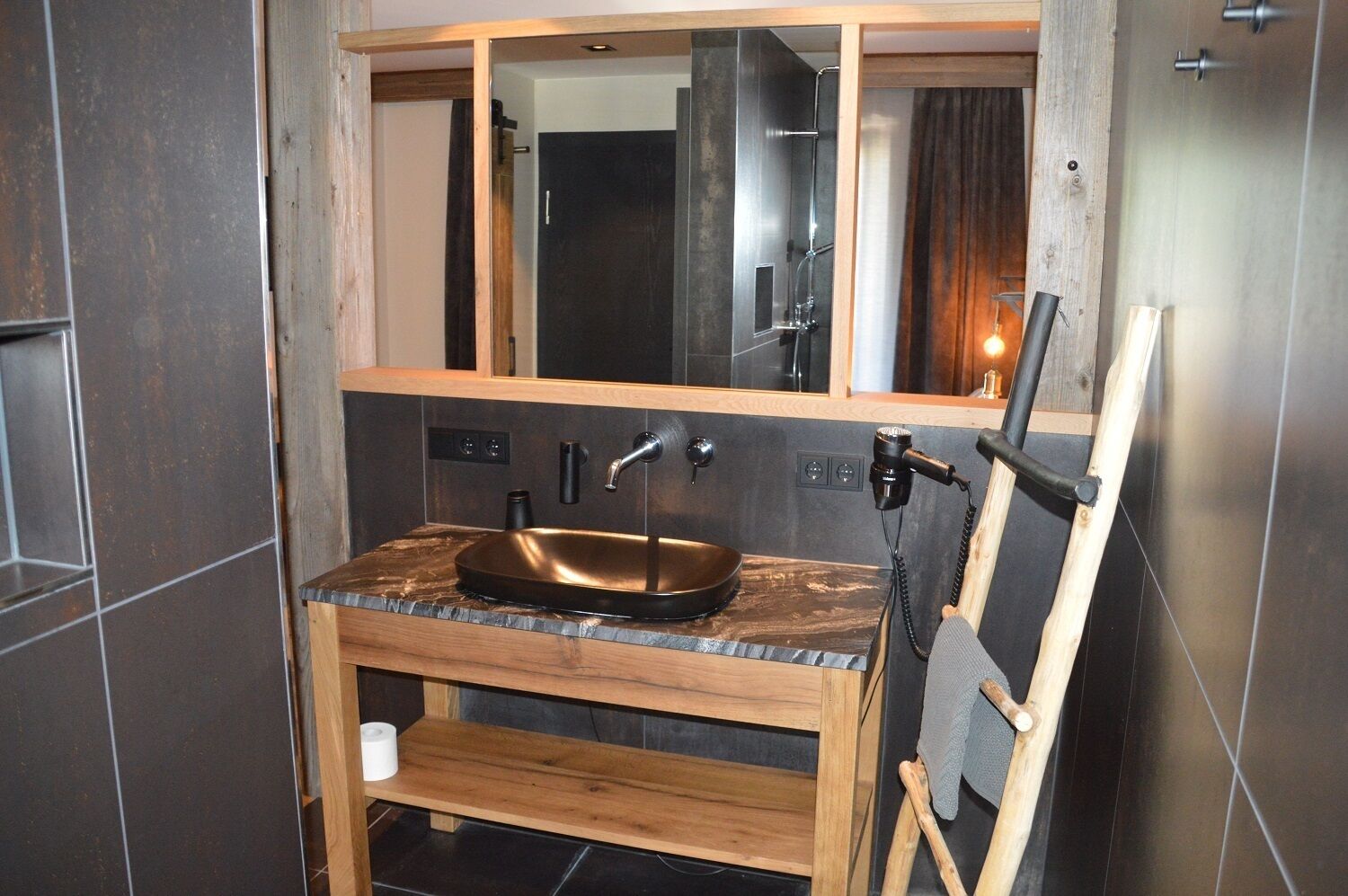 A bathroom with a wooden vanity, a copper sink, and a large mirror.