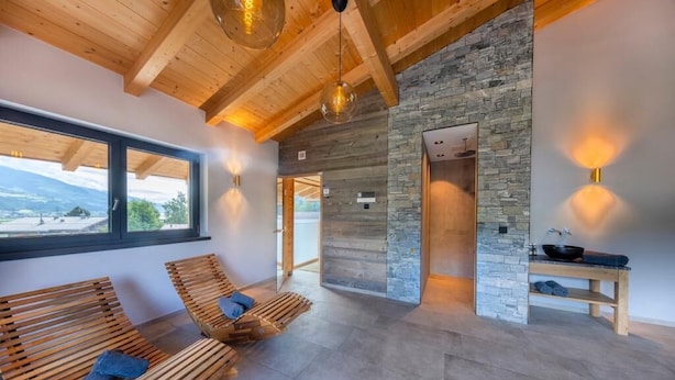 A spa room with wooden benches, a stone wall, and a view of the outdoors. - Hotel Herz3 (Hollersbach im Pinzgau)