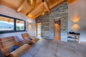 Un cuarto de spa con bancos de madera, pared de piedra y vista al exterior.