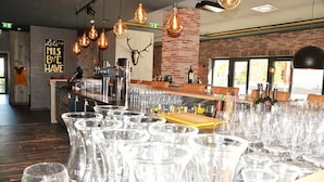 A bar area with a rustic brick wall, a mounted deer skull, and a 'Let's Miss Bye Have' sign. - Hotel Herz3 (Hollersbach im Pinzgau)