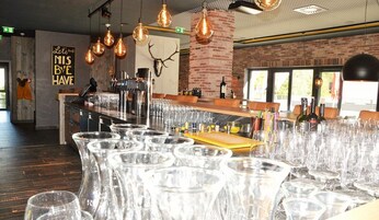 Un área de bar con pared de ladrillo rústica, una calavera de venado montada y un letrero que dice 'Let's Miss Bye Have'.