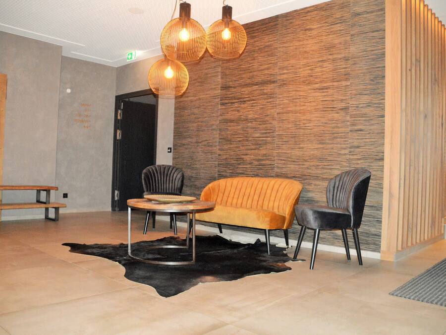 A modern lobby with a sofa, chairs, a round table, and a unique wall design.