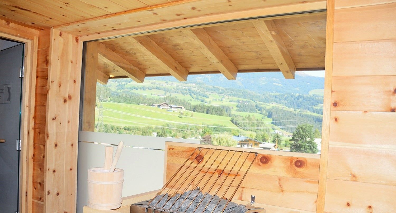 A wooden cabin with a view of green hills and a wooden grill outside.
